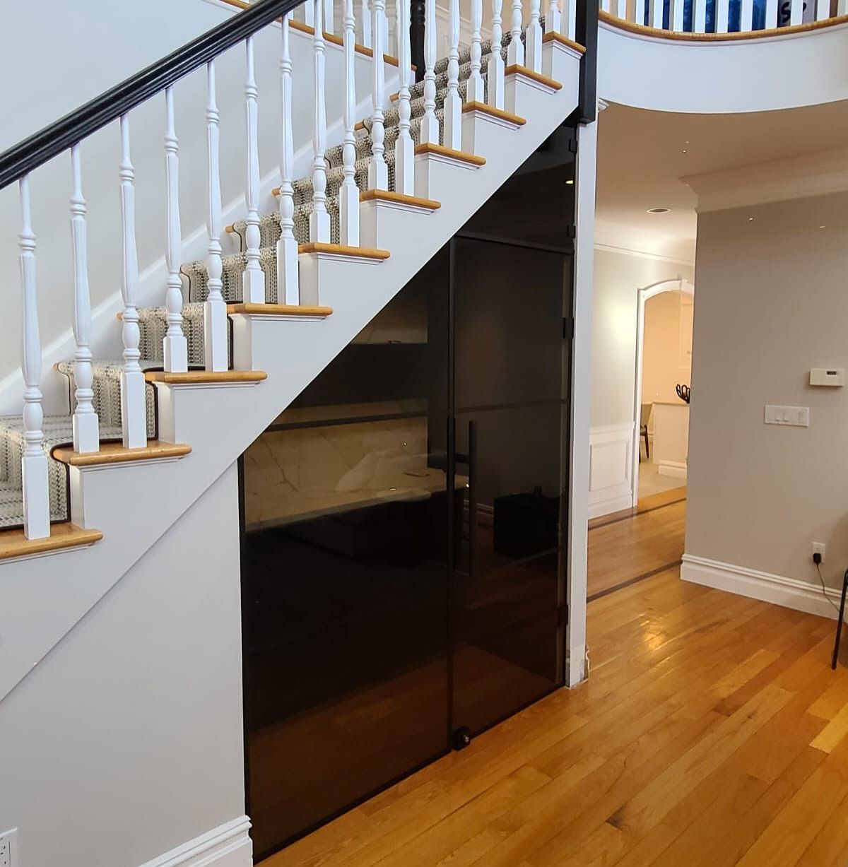 A staircase in a house with a black door underneath it