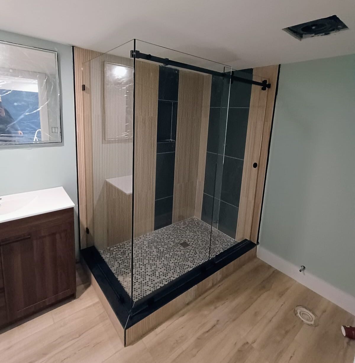 A bathroom with a walk in shower and a sink