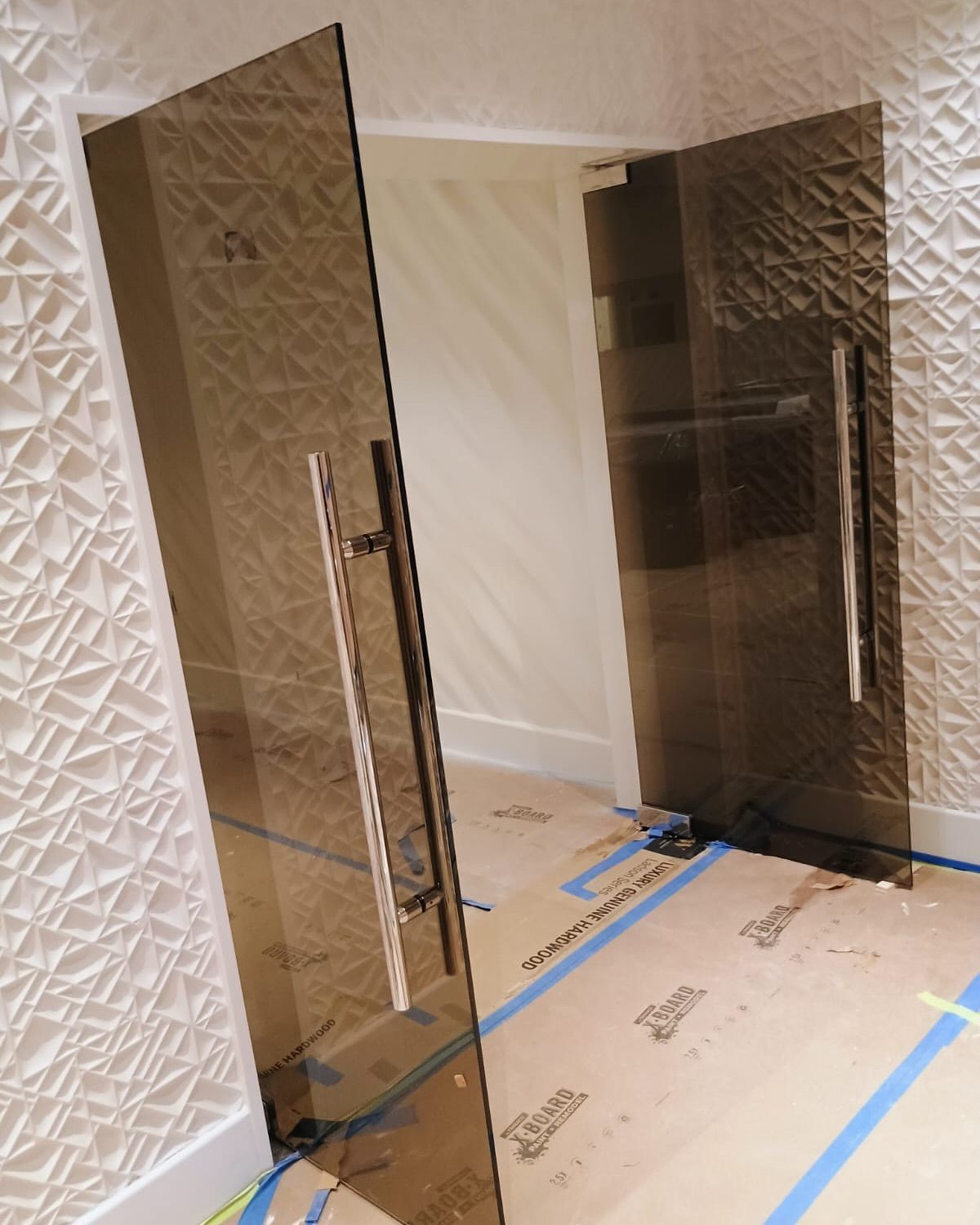 A hallway with a glass door and a white wall