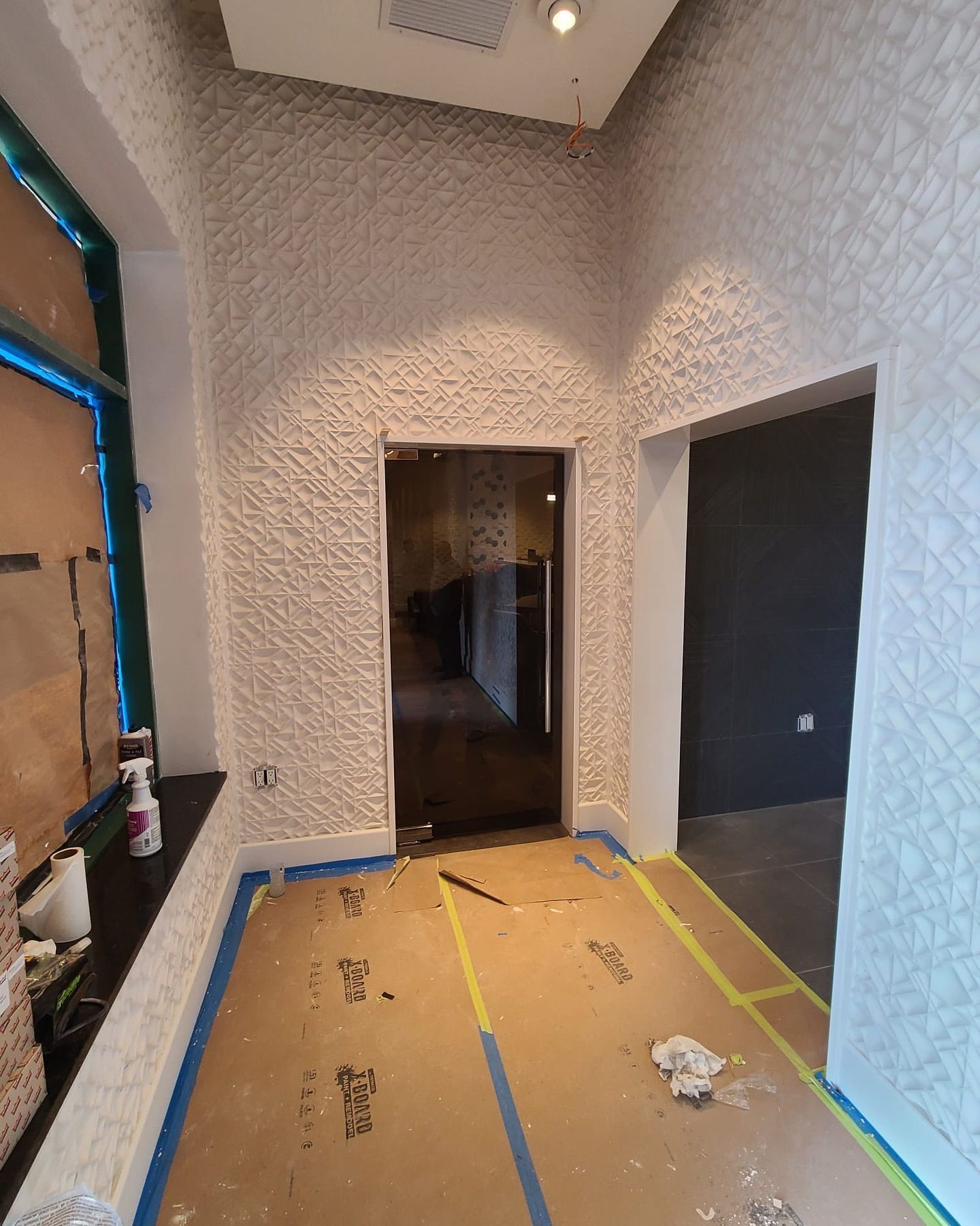 A hallway with a door and a window in a building under construction.