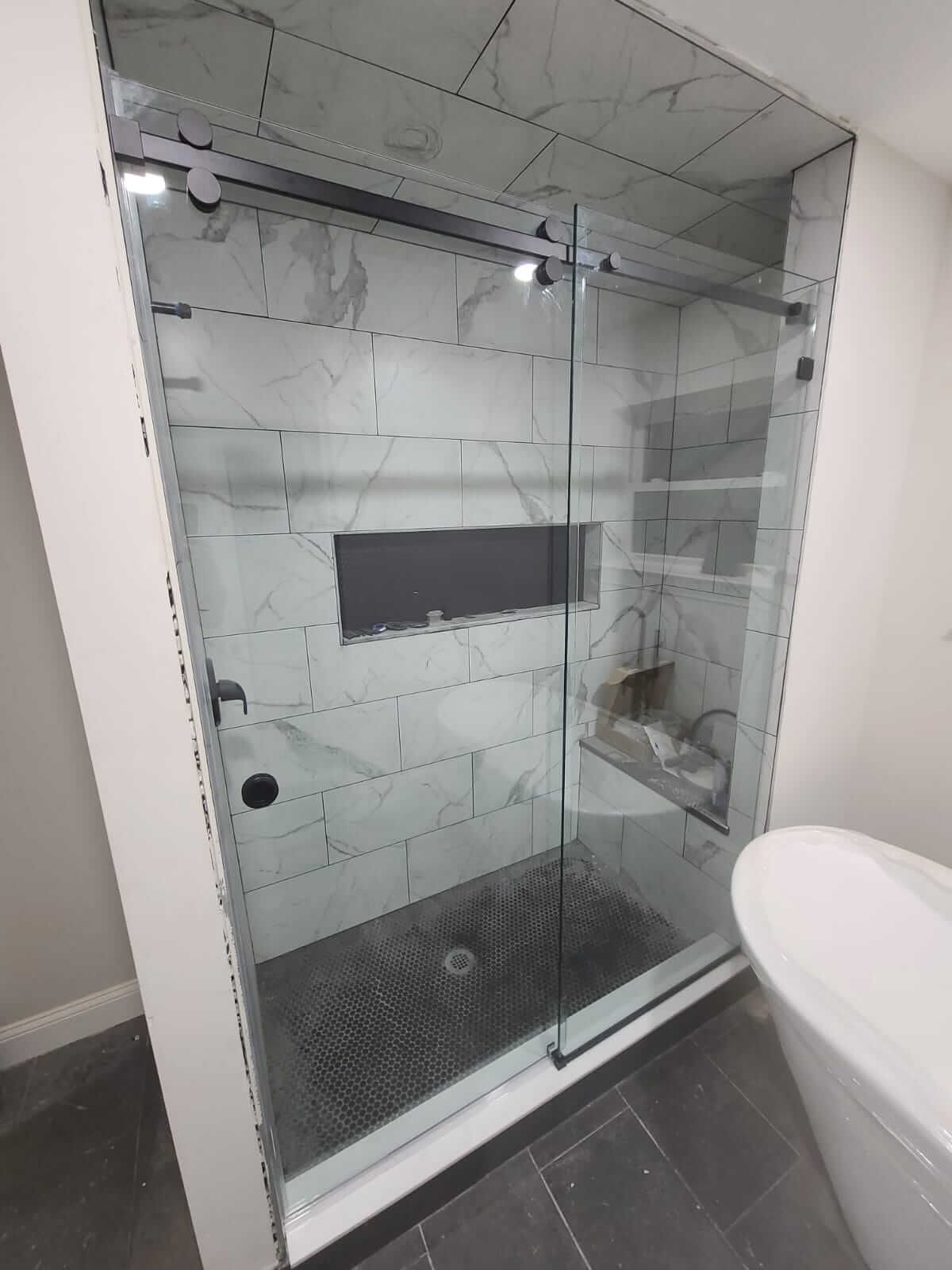 A bathroom with a sliding glass shower door and a bathtub.