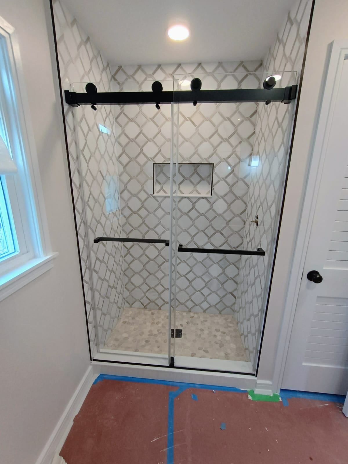 A bathroom with a sliding glass shower door and a window.
