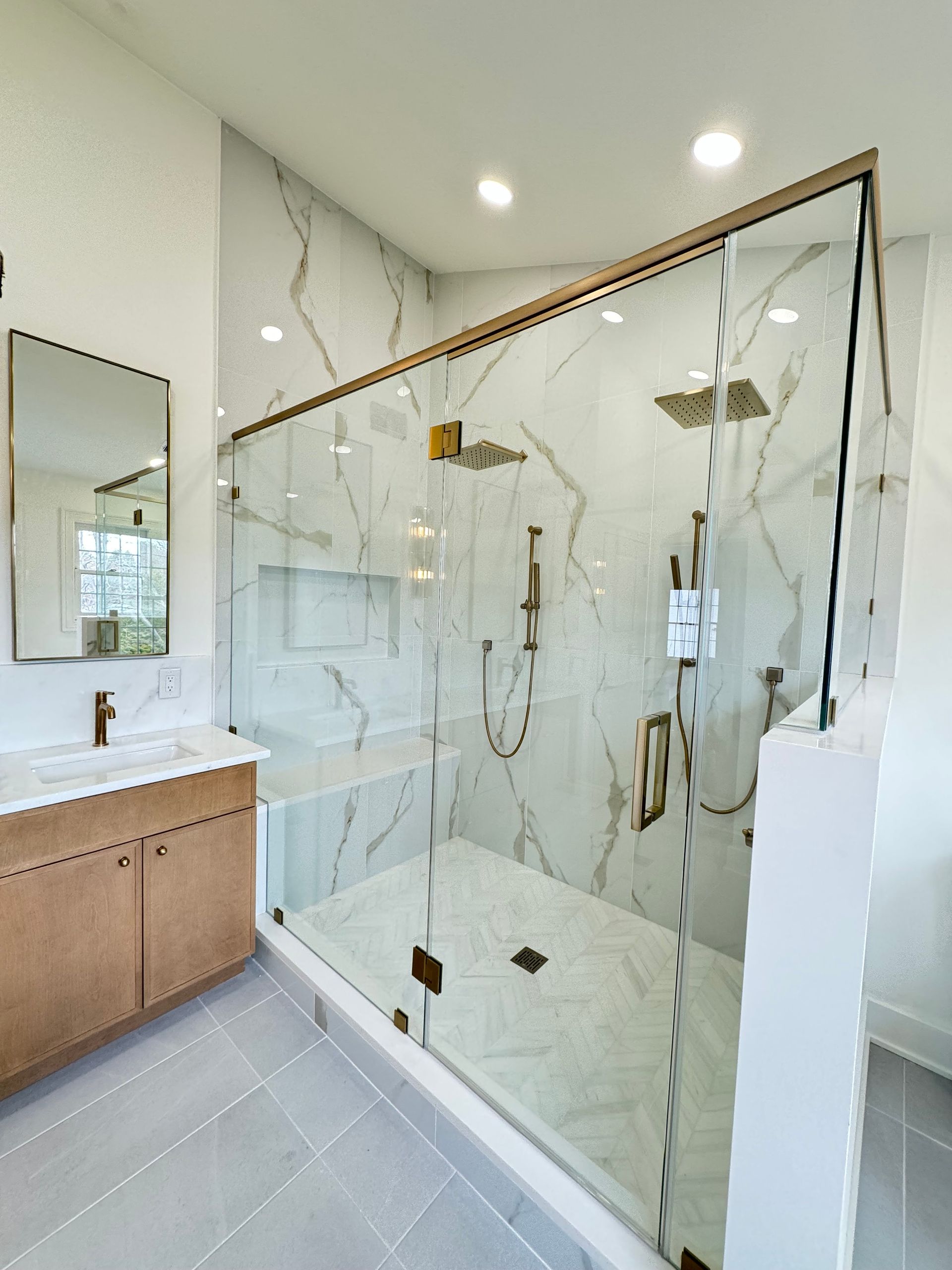 A bathroom with a walk in shower , sink and mirror.