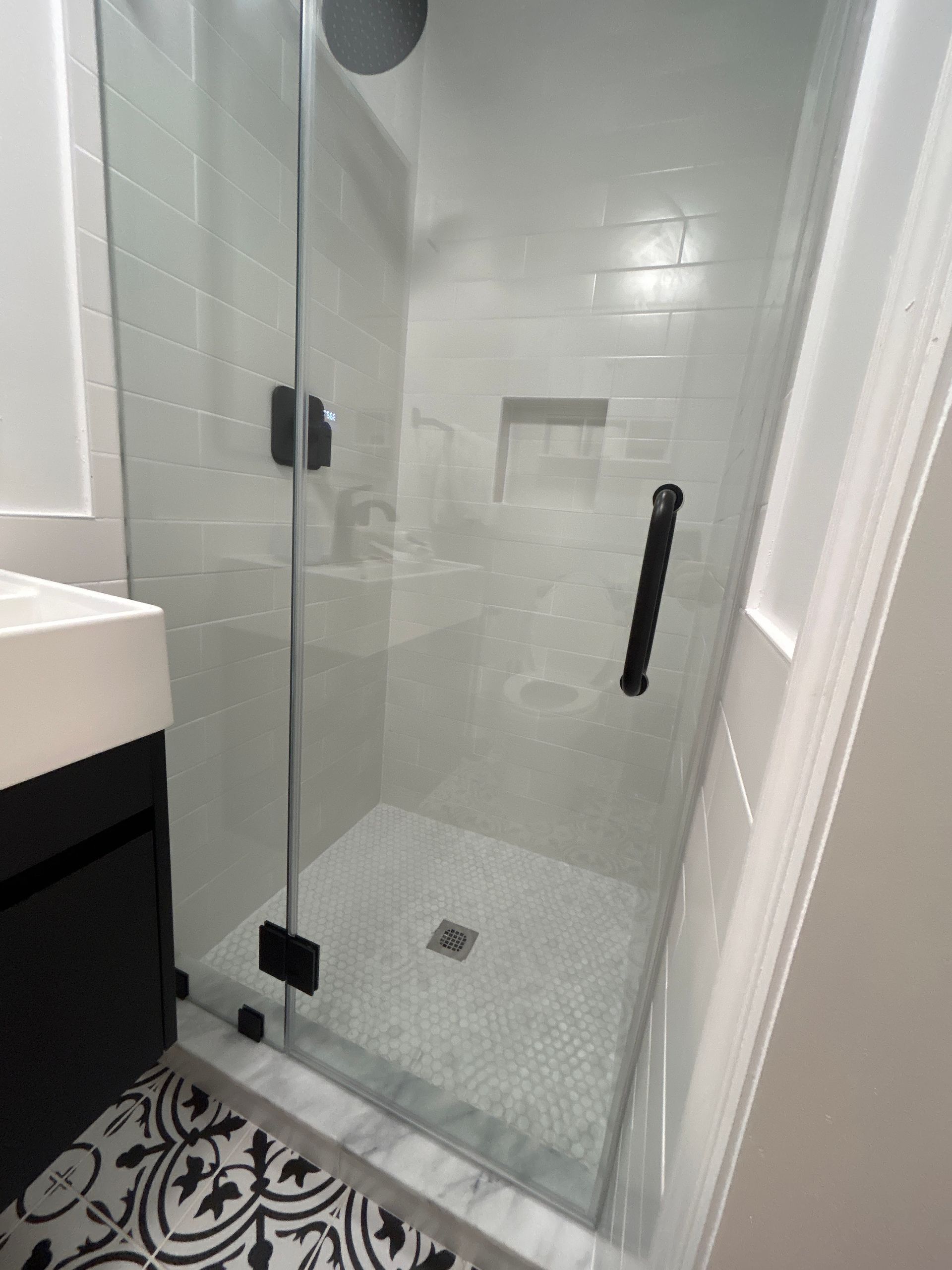 A bathroom with a walk in shower and a sink.