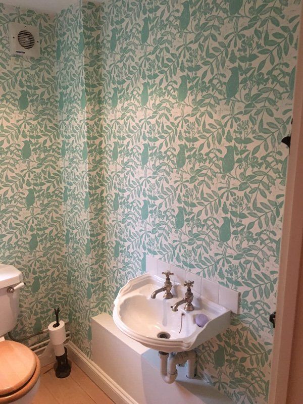 Sink on a wall with blue and white wallpaper