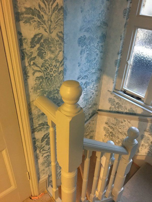 Grey and blue floral wallpaper and white banister