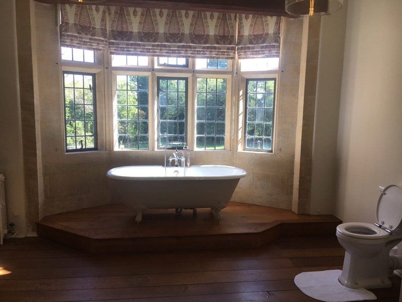 Traditional white bath tub under windows