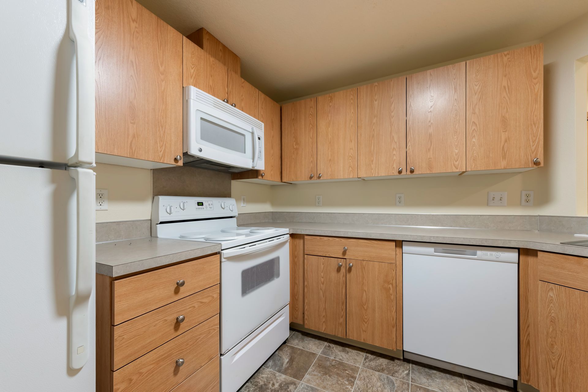 A kitchen with a stove , refrigerator , dishwasher and microwave.
