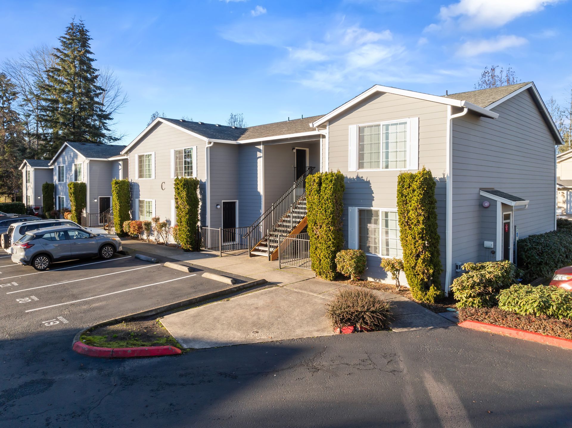 A row of apartment buildings with cars parked in front of them