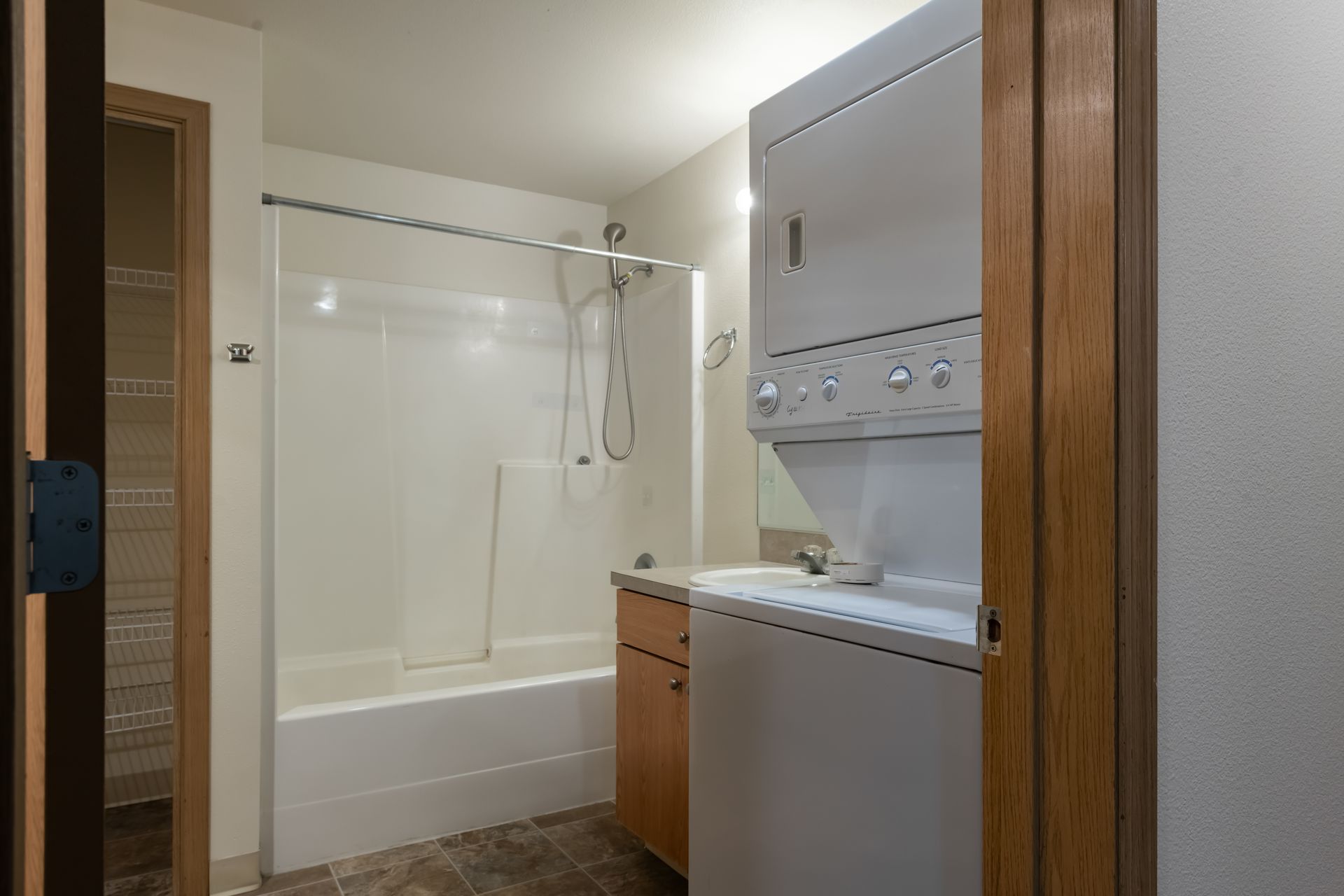 A bathroom with a washer and dryer and a bathtub.