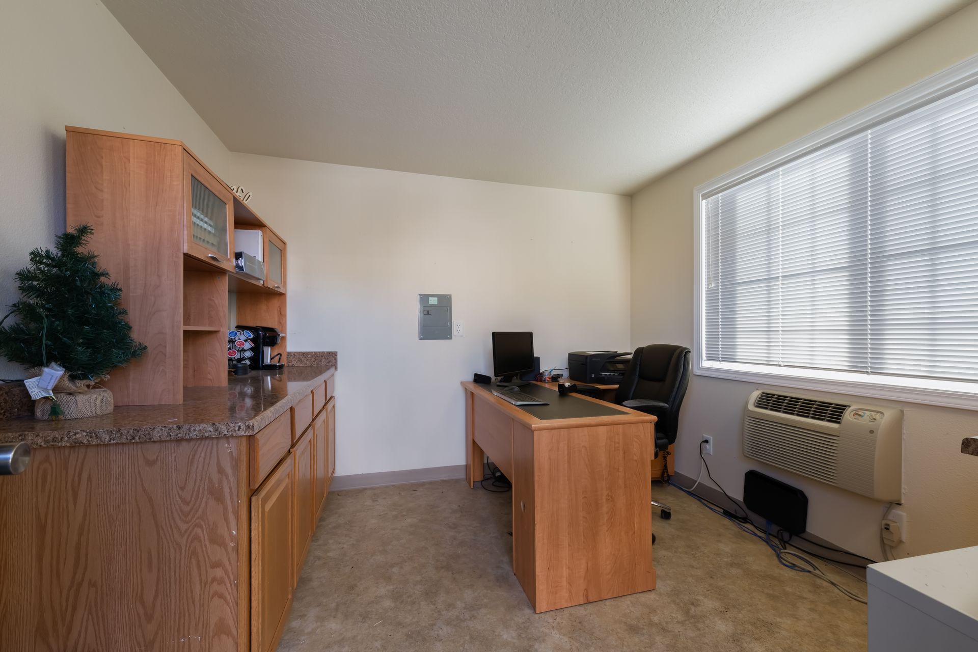 A room with a desk and a window with blinds