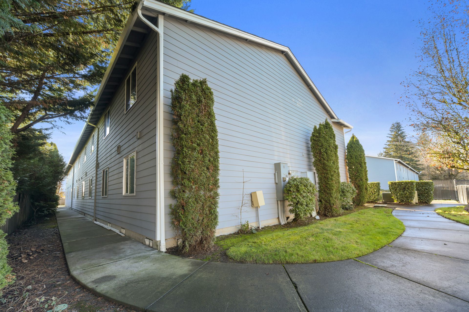 A house with a sidewalk and trees in front of it.