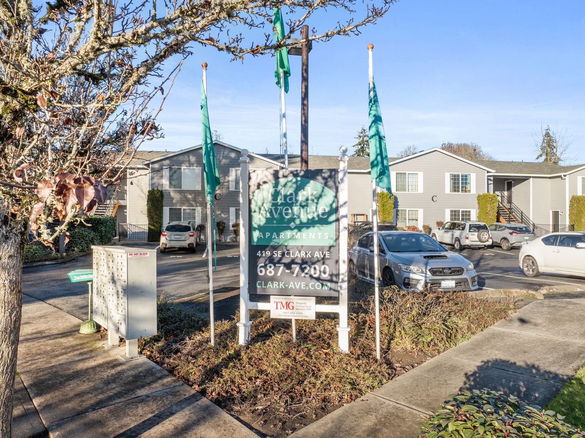 A sign in front of a building with cars parked in front of it.
