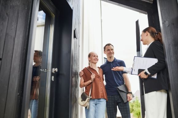 a man and woman are standing in front of a house talking to a real estate agent .