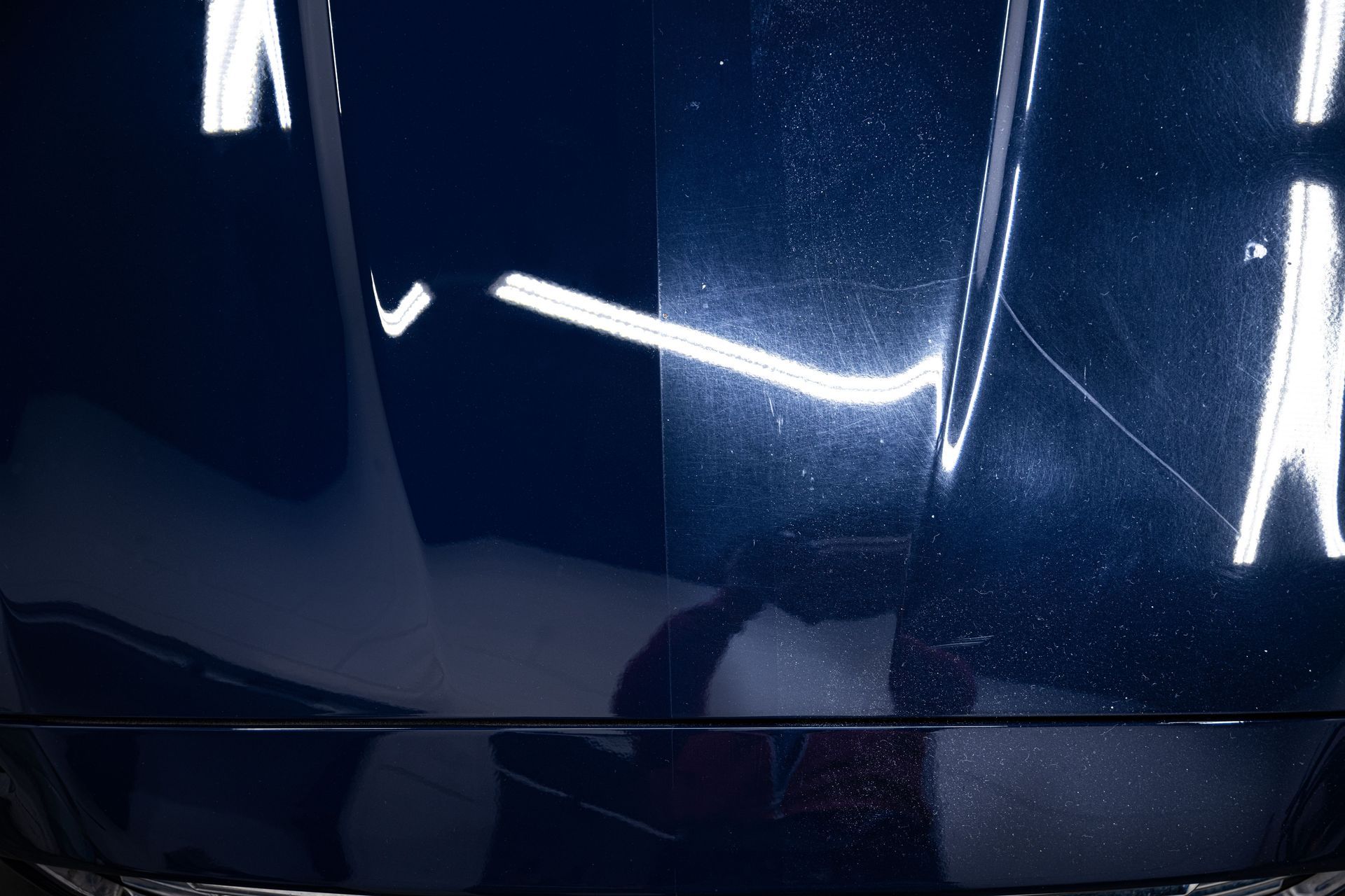 A close up of a car hood before and after being polished.