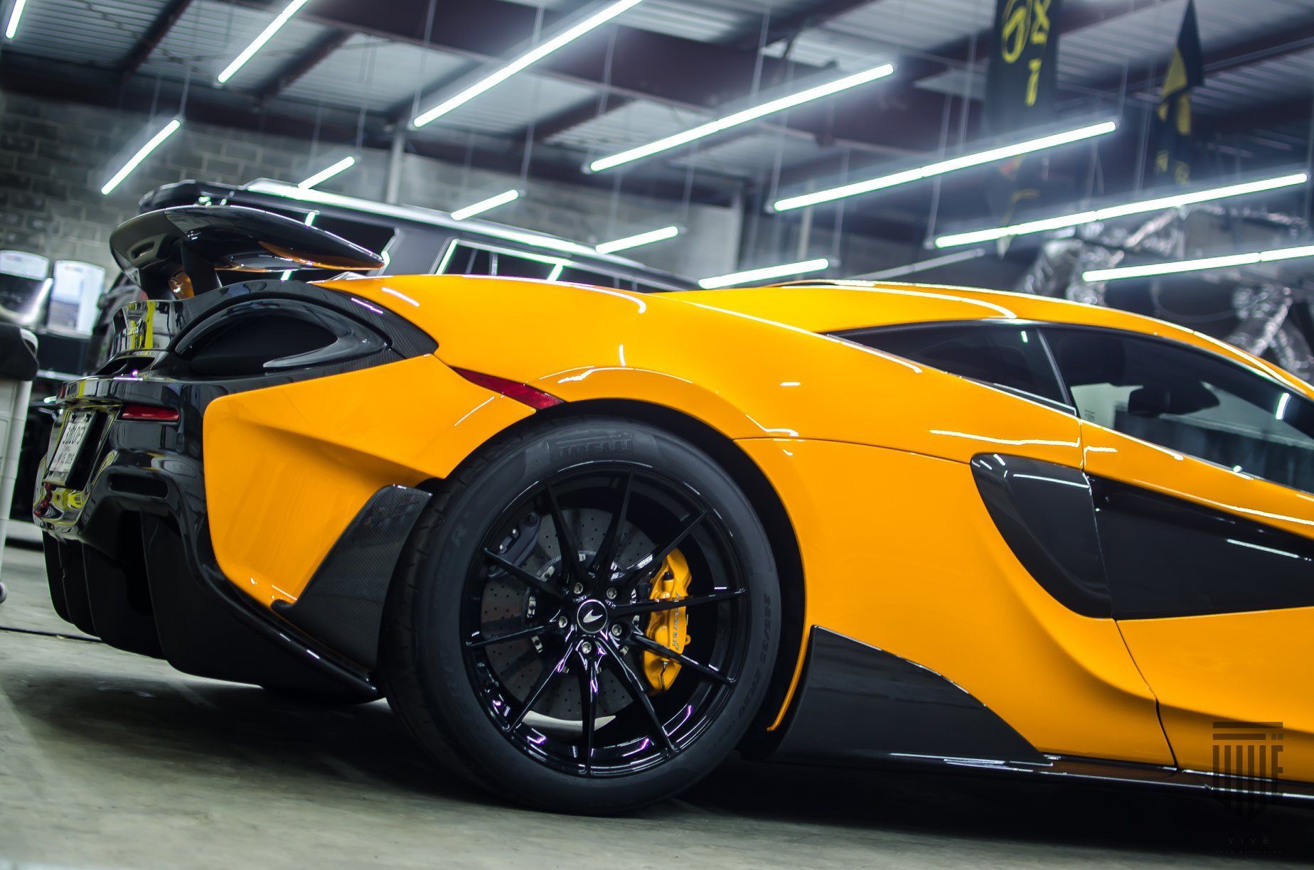 A yellow and black sports car is parked in a garage.