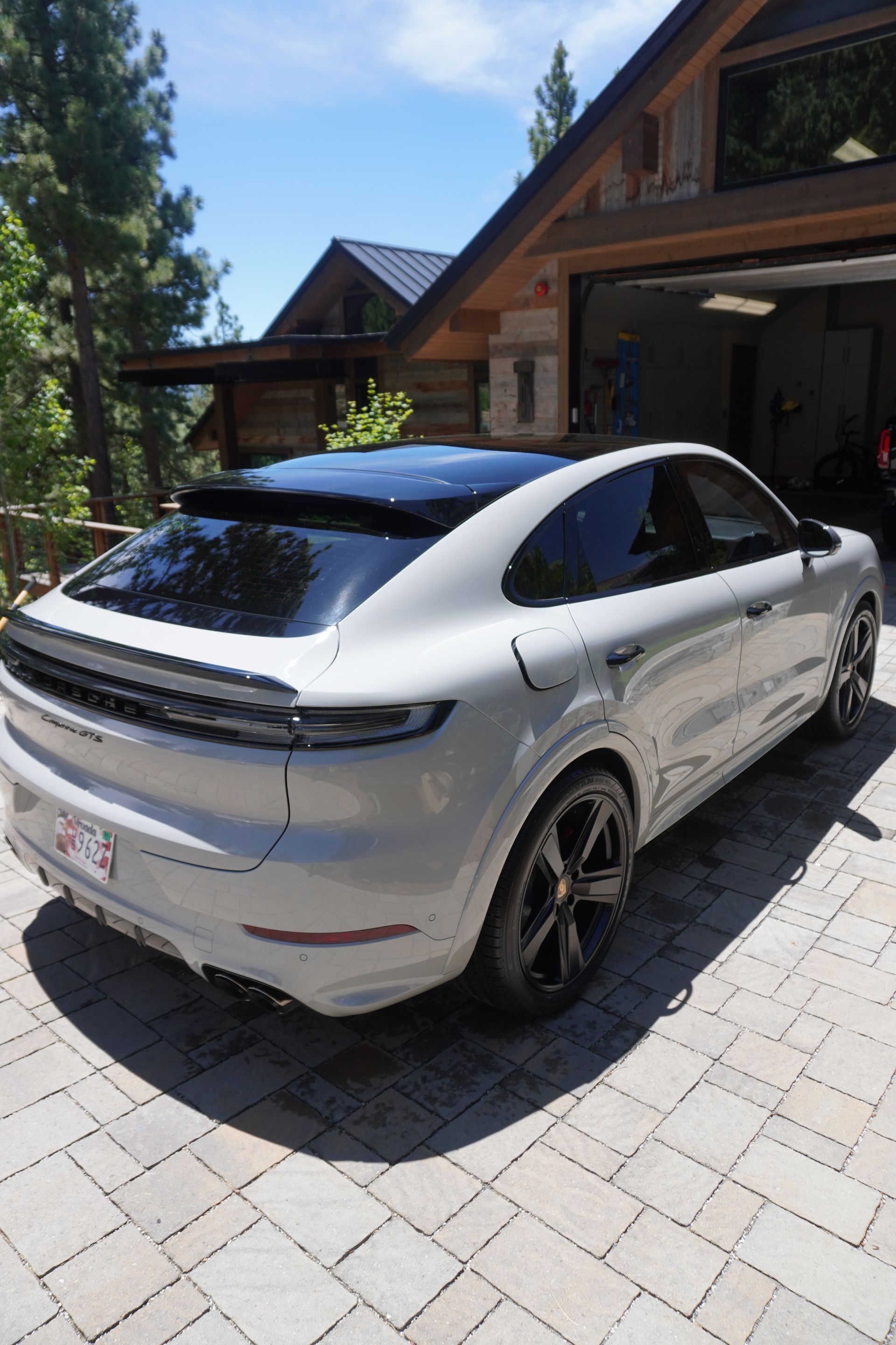 A white porsche cayenne is parked in front of a house.