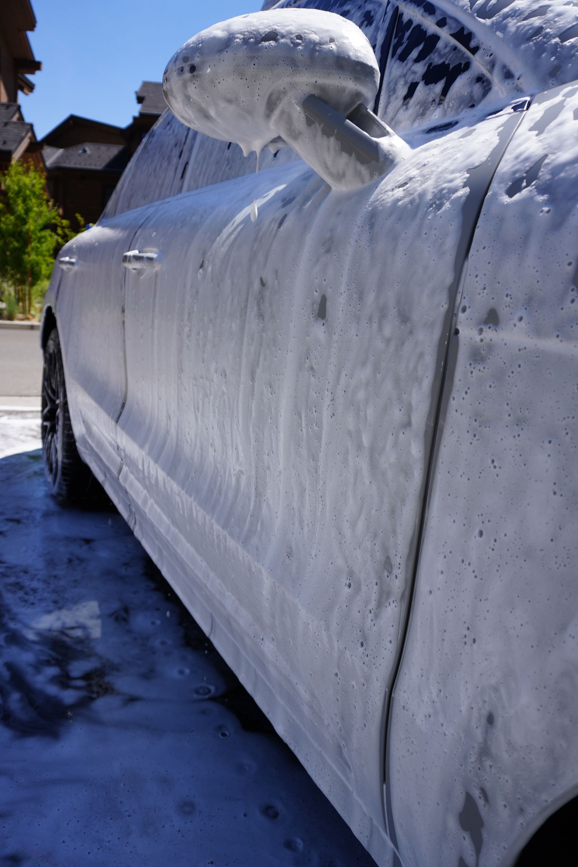 A white car is covered in foam and soap.