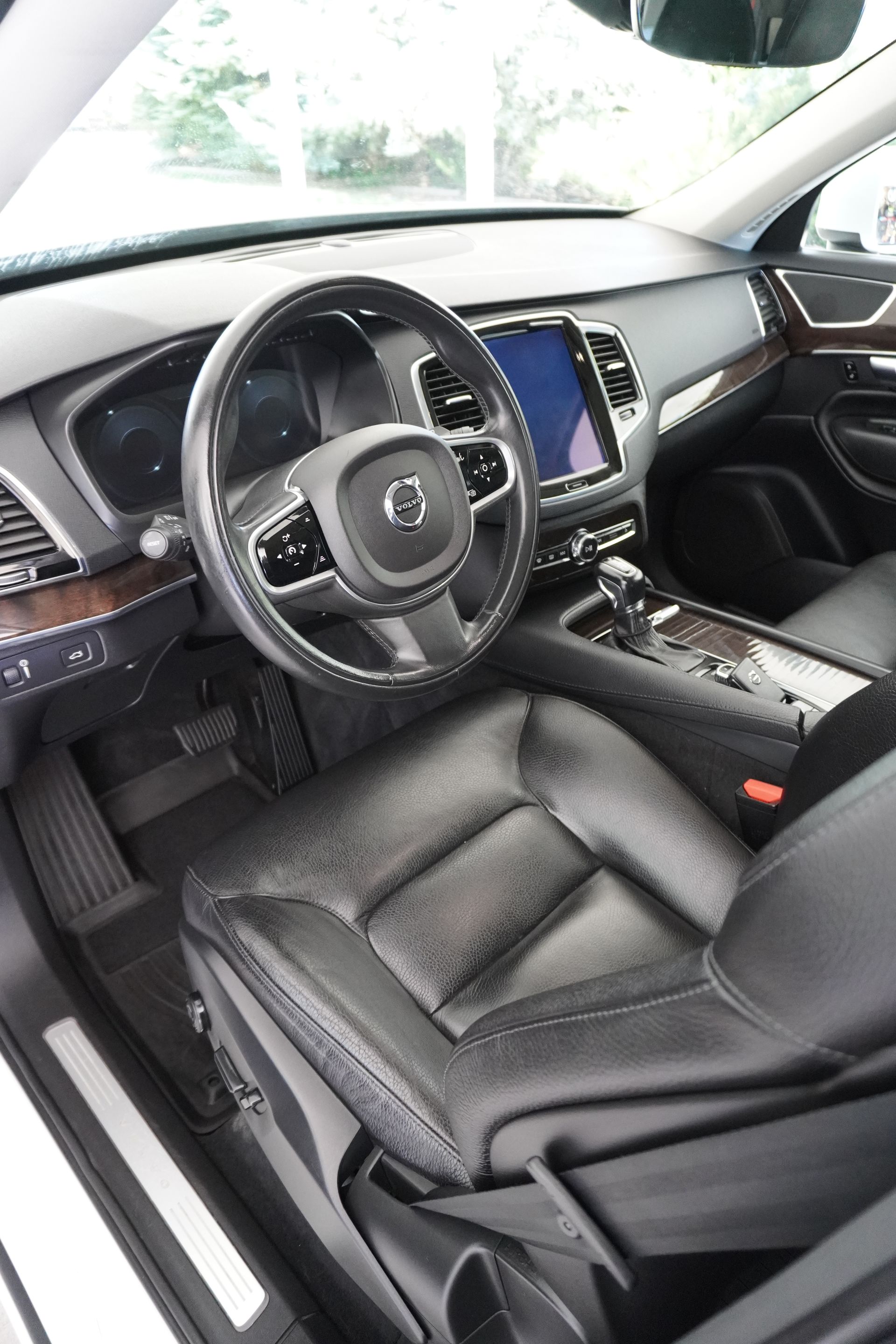 The interior of a volvo xc90 with black leather seats and a steering wheel.