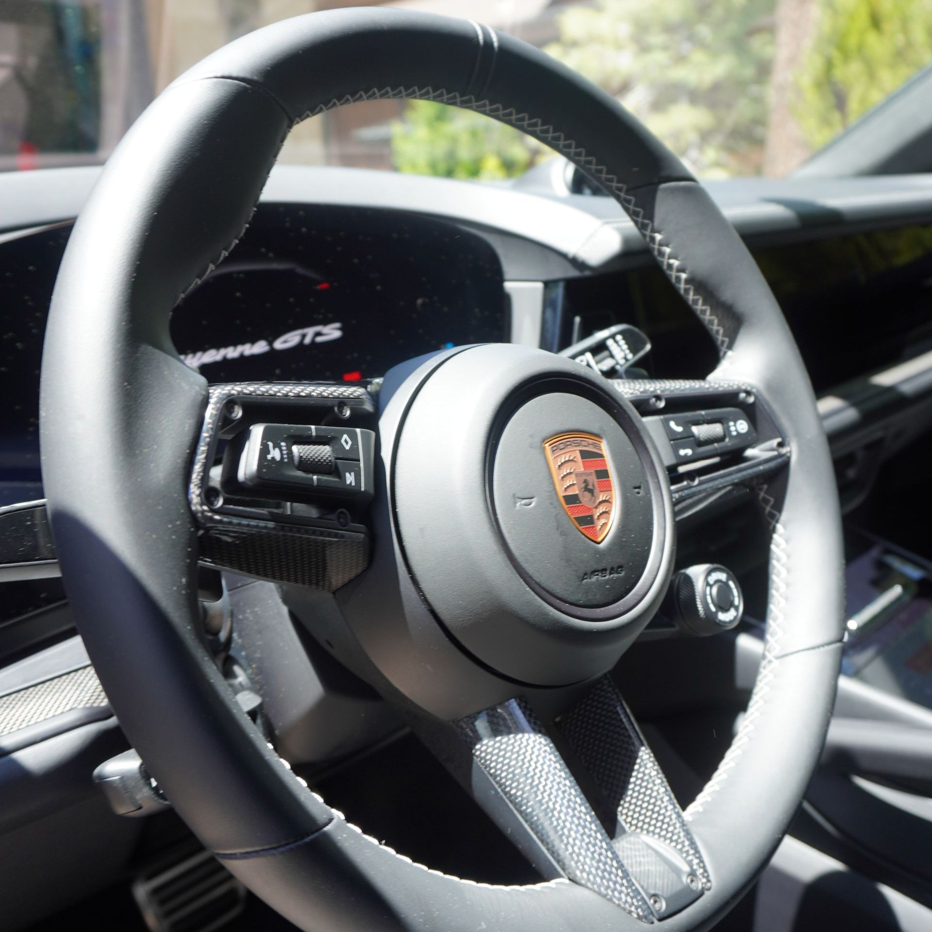 A close up of a porsche steering wheel in a car