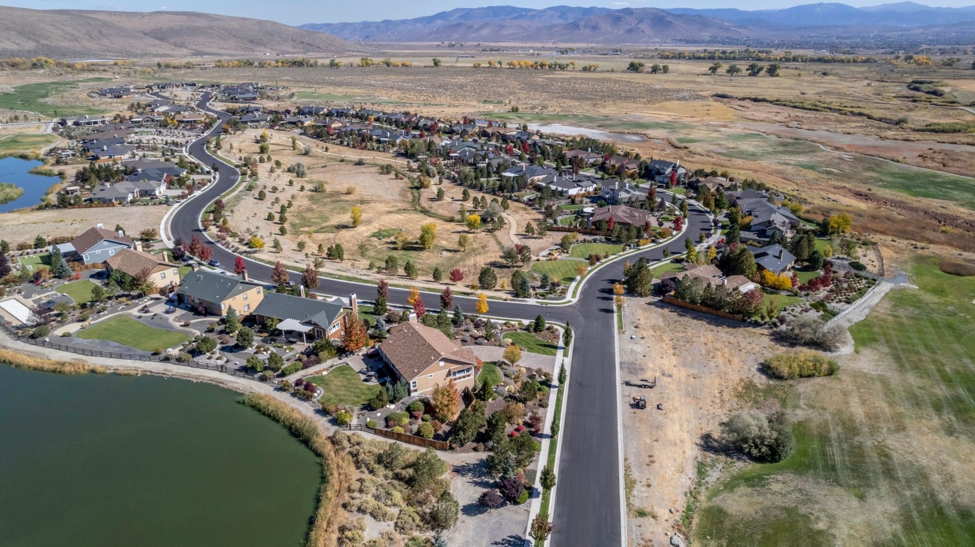 An aerial view of a residential area with a lake and mountains in the background.