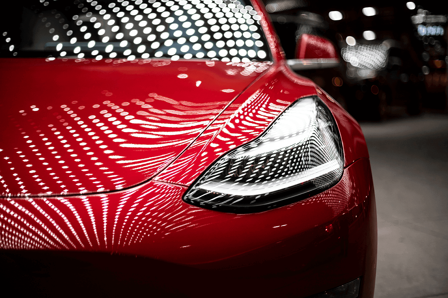A close up of the front of a red tesla model 3.