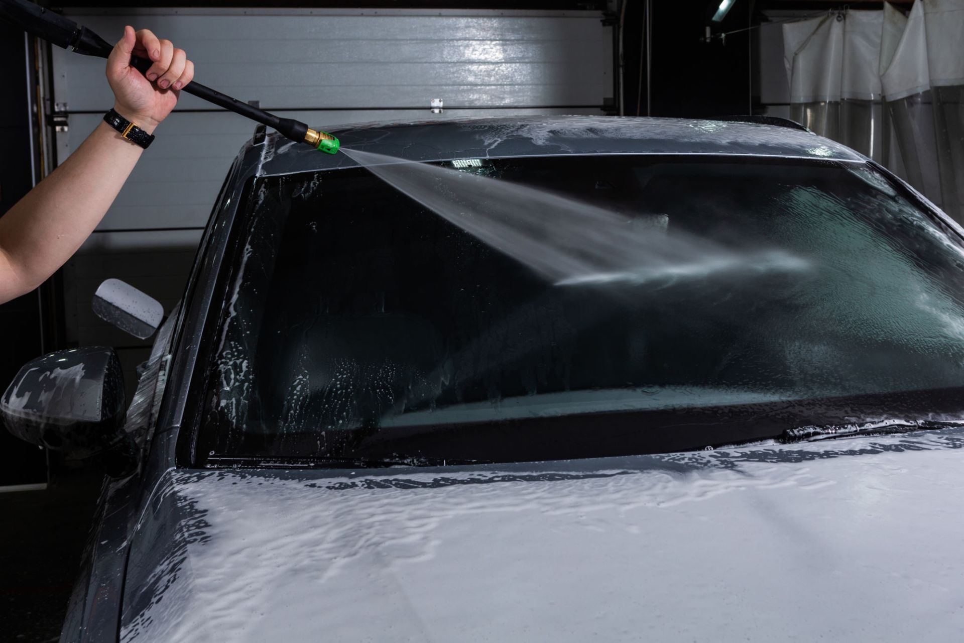 A person is washing a car with a high pressure washer.