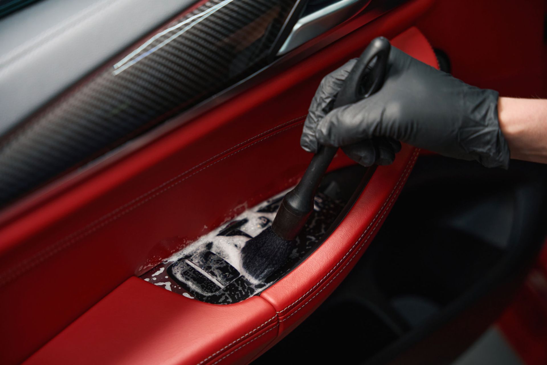 A person is cleaning the interior of a car with a brush.