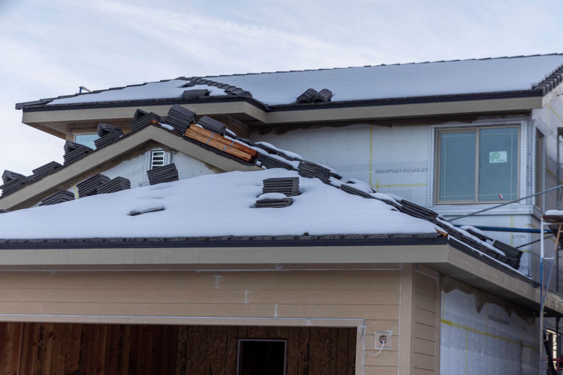 A house under construction with snow on the roof.