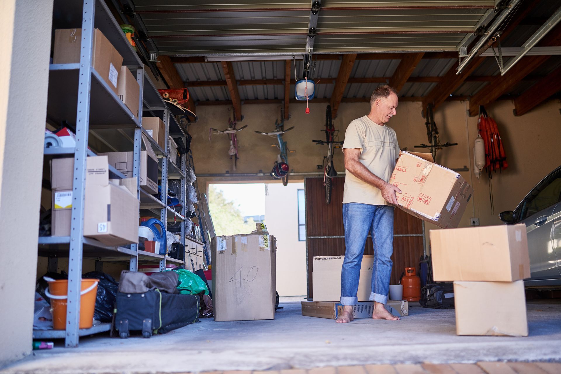 A man is carrying a box in a garage.