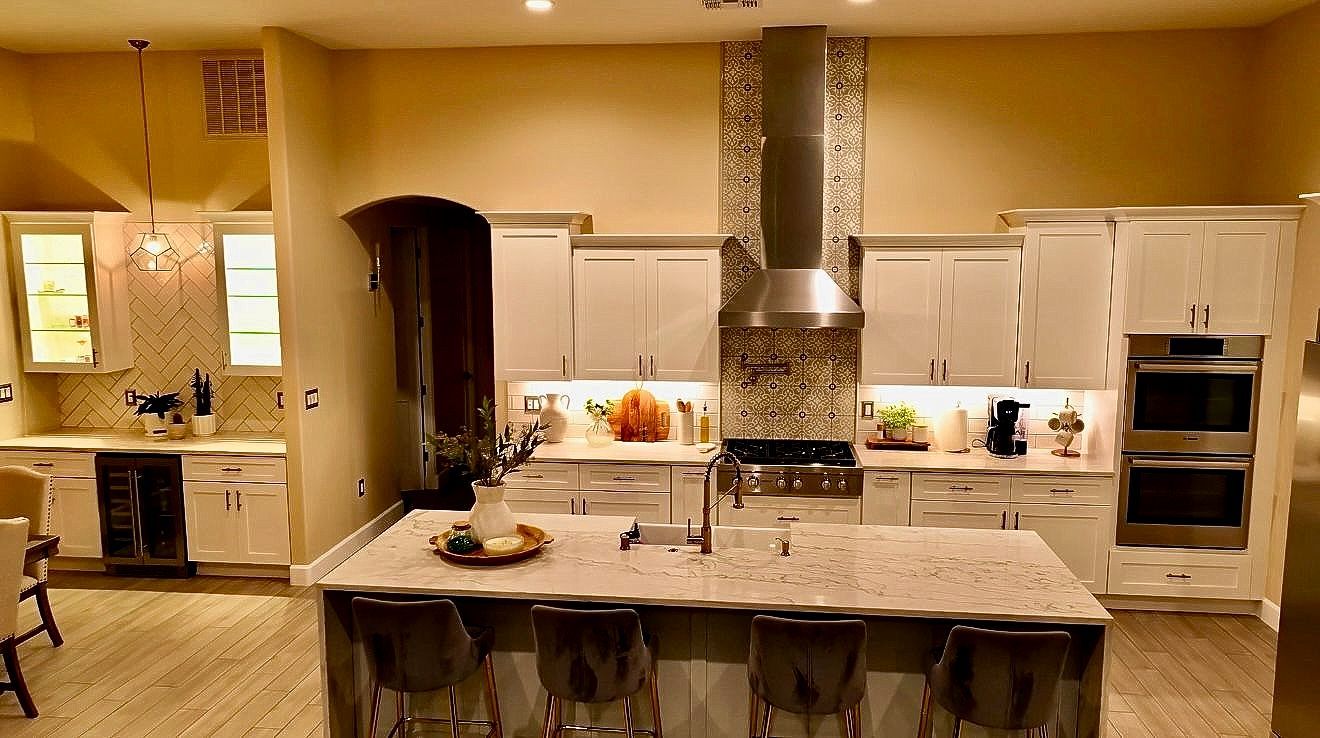 A kitchen in a house under construction with white cabinets and granite counter tops.