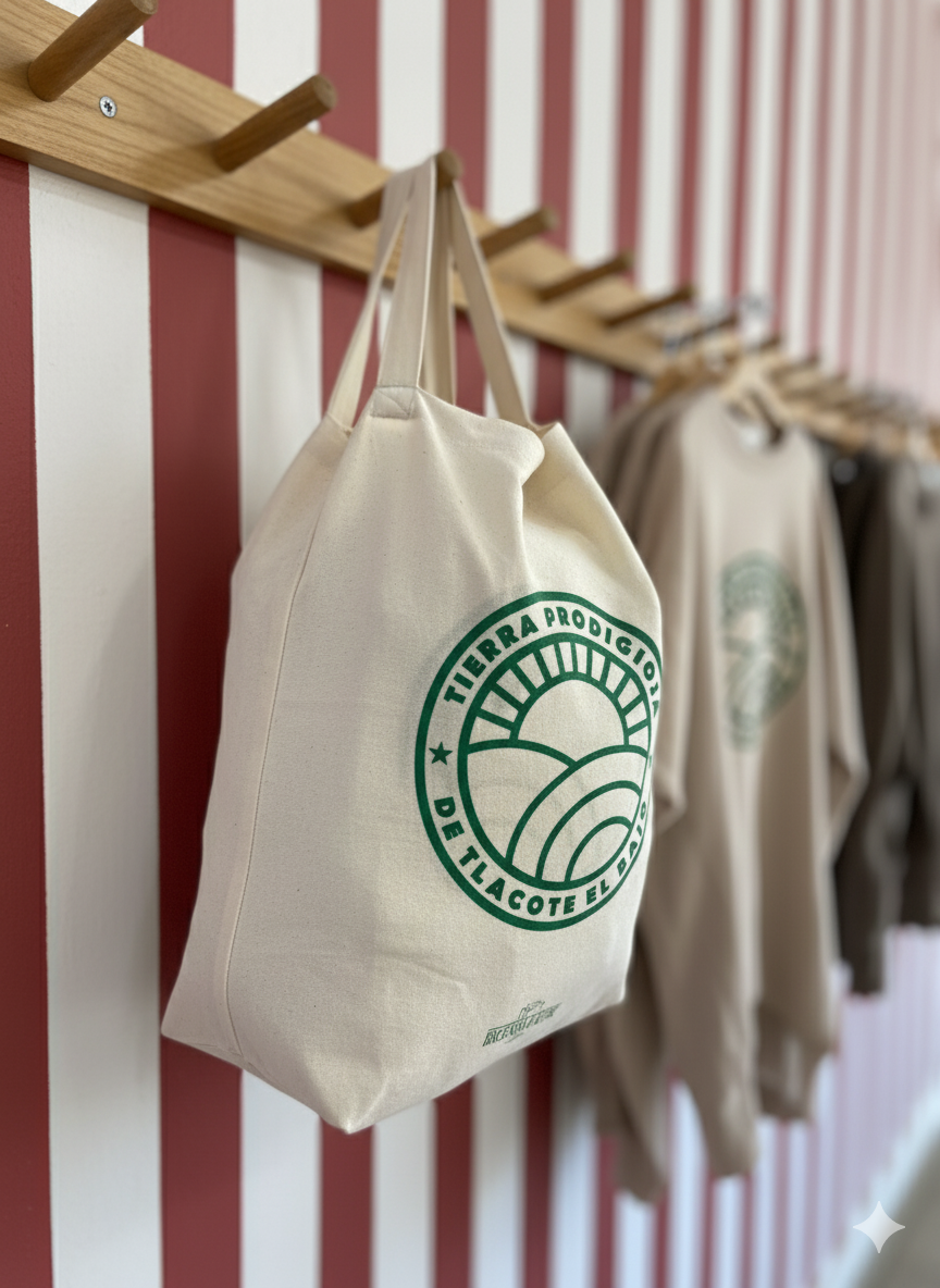 Una bolsa de tela color crema con un logotipo verde cuelga de una pared con rayas rojas y blancas.