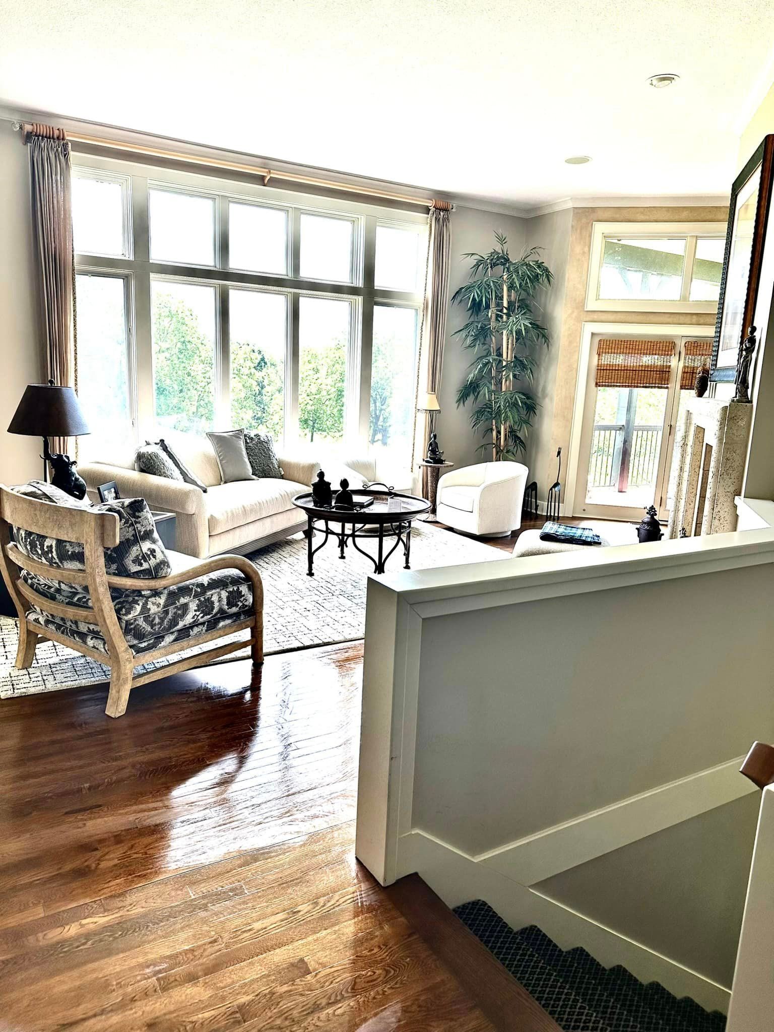 A living room with a couch , chair , coffee table and stairs.