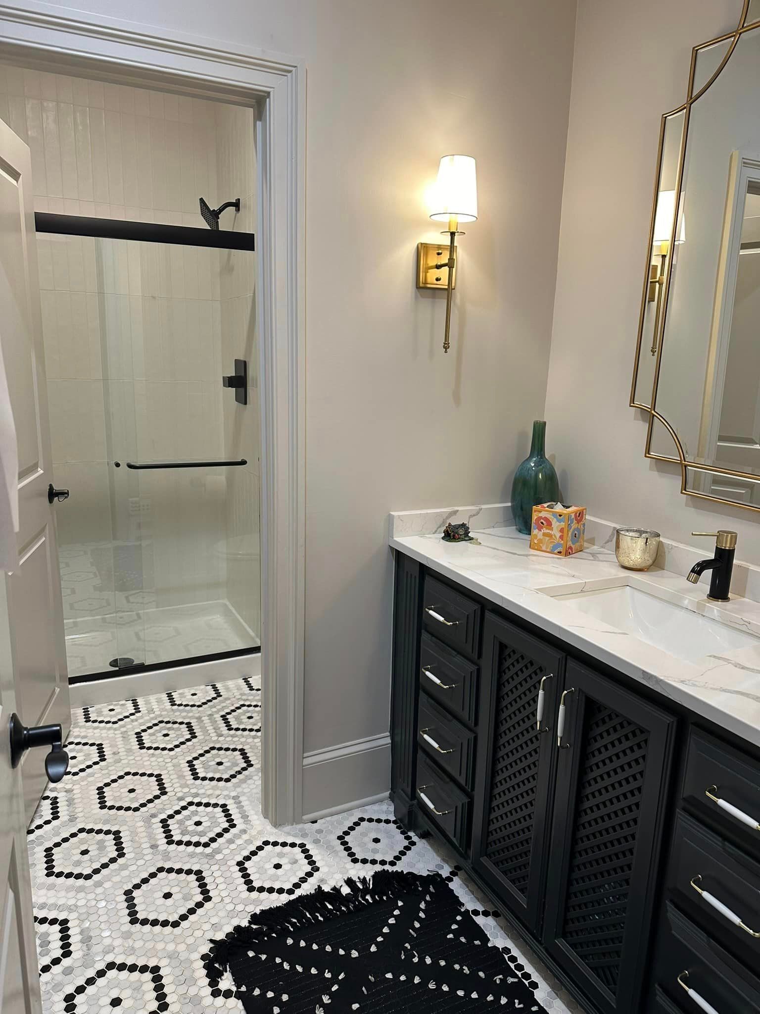 A bathroom with two sinks , a mirror and a walk in shower.