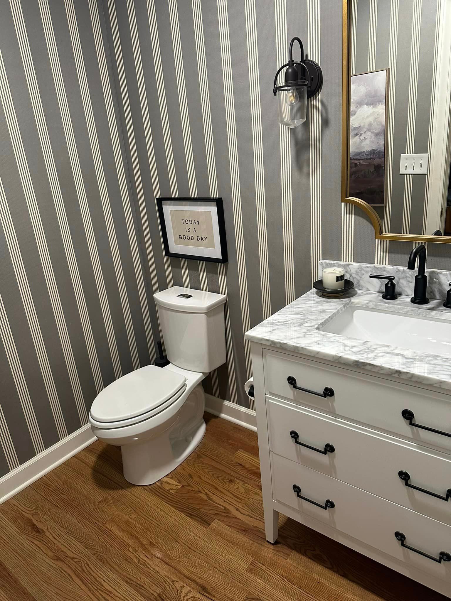 A bathroom with a toilet , sink , dresser and mirror.