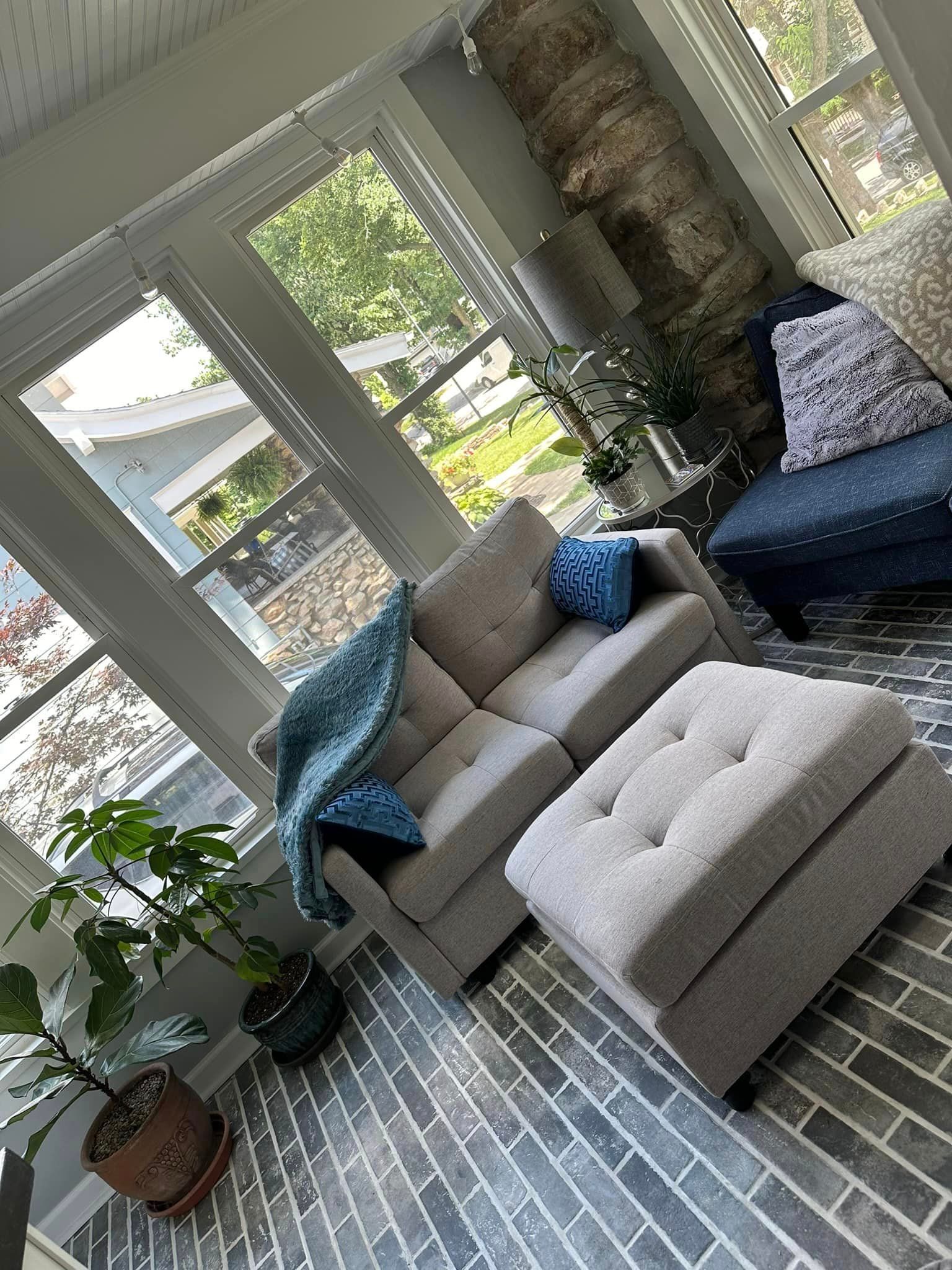 A living room with a couch , chair , and ottoman.