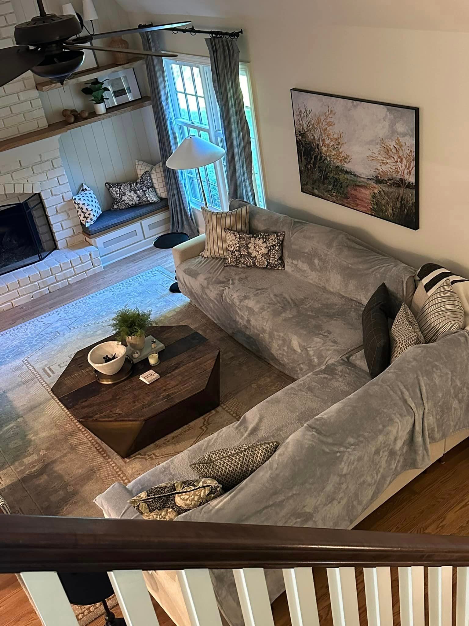 An aerial view of a living room with a couch , coffee table and fireplace.