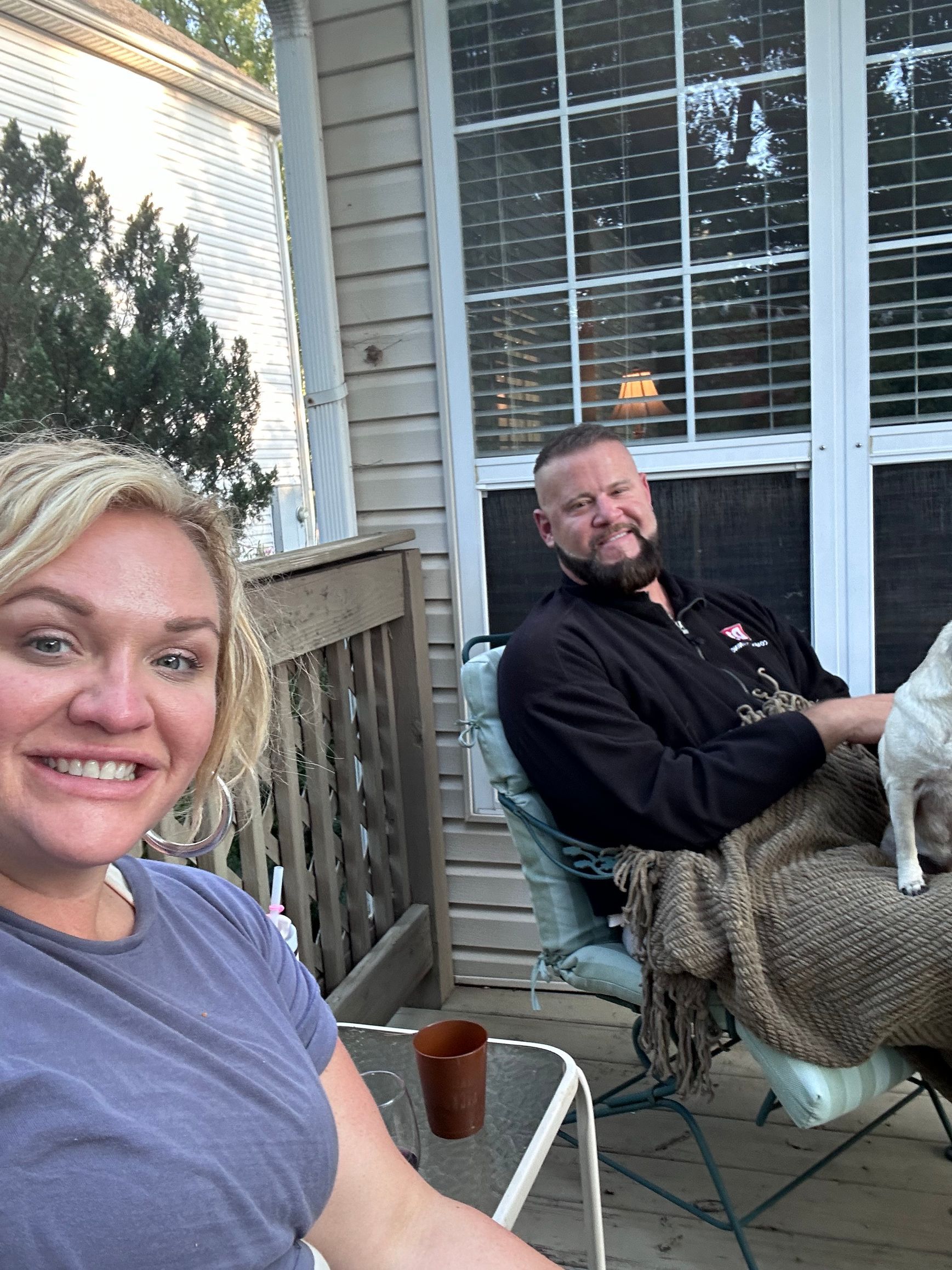 A man and a woman are sitting on a porch with a dog.