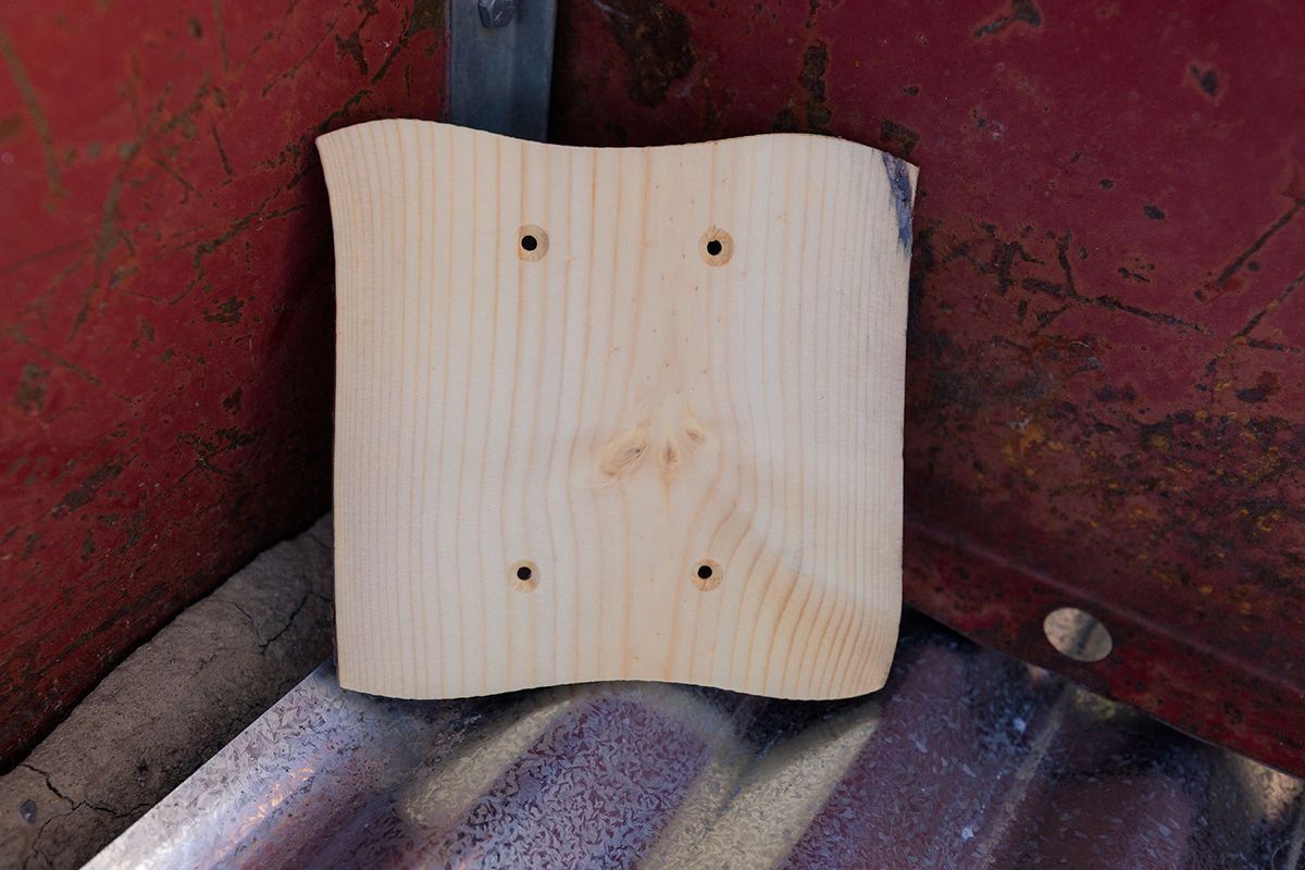 A piece of wood with holes in it is sitting on a metal surface.