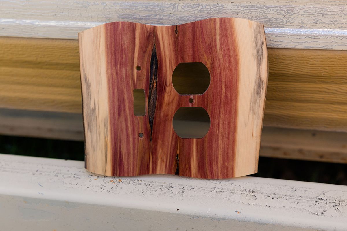 A piece of wood with two holes in it is sitting on a railing.