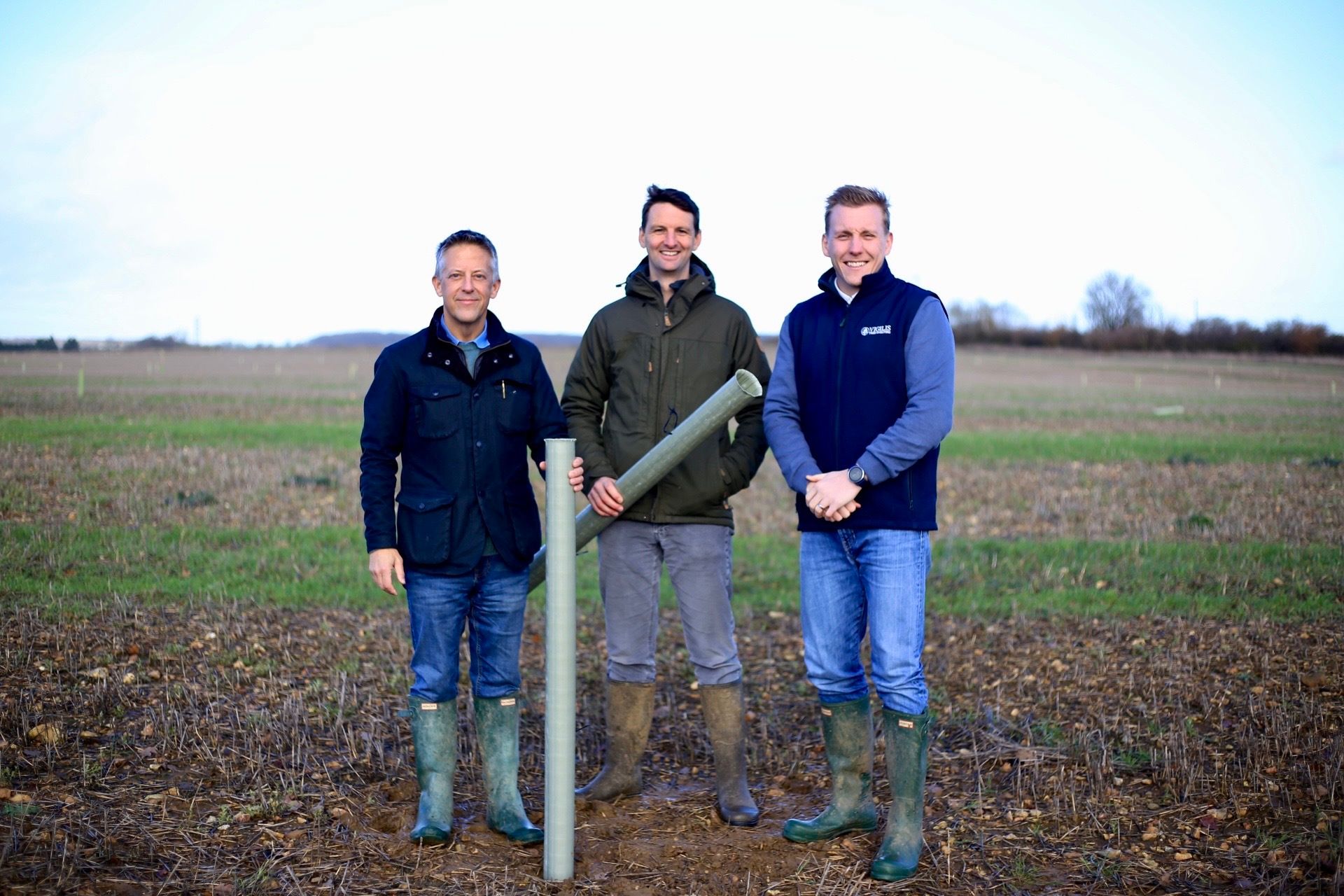 Representatives from Spains Hall estate and Vigilis Tree shelters stand in a field with newly planted trees