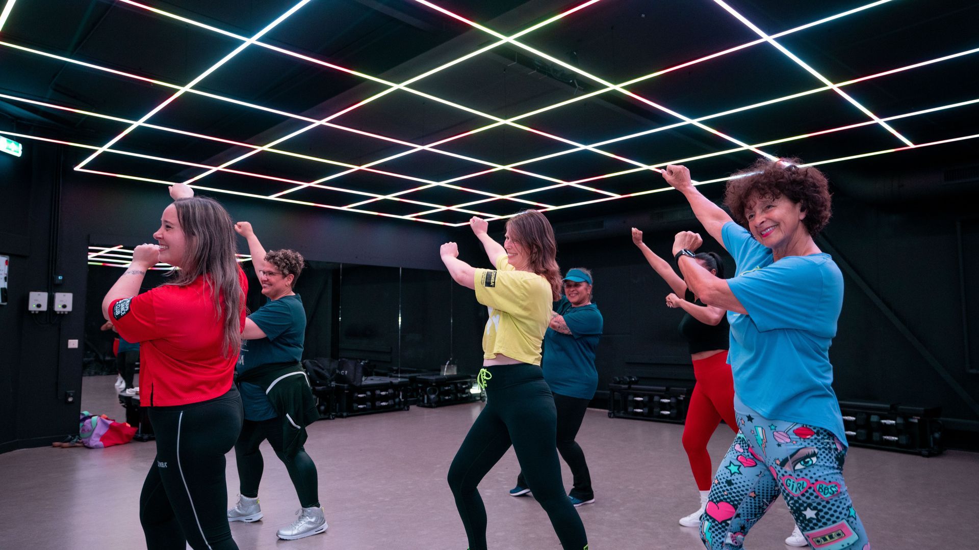 Een groep vrouwen doet oefeningen op yogamatten in een sportschool.