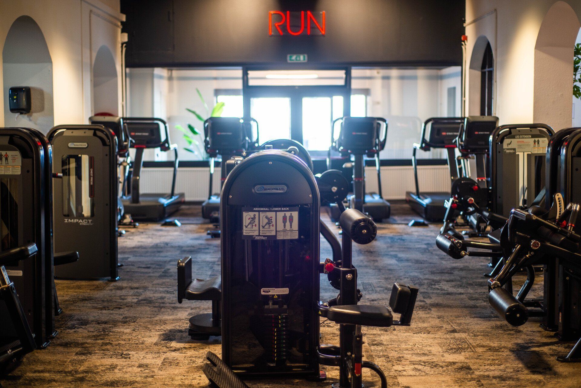 Een sportschool vol met fitnessapparatuur en een bord waarop 'ren' staat.