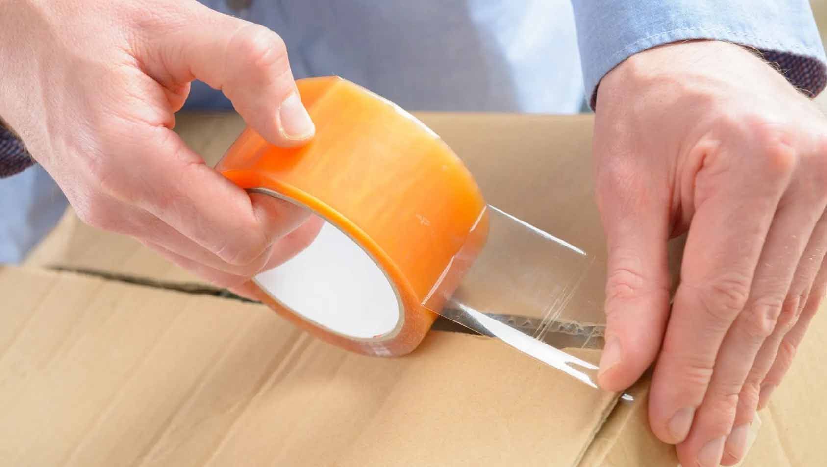 A person is wrapping a cardboard box with tape.