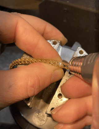 A person is working on a bracelet with a machine