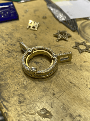 A gold ring with diamonds is sitting on a wooden table.