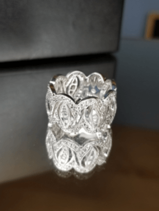 A silver ring with diamonds is sitting on a table.