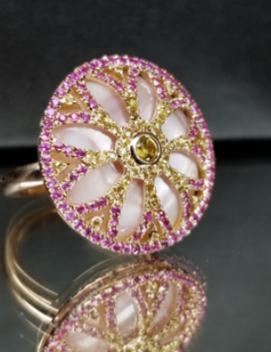 A gold ring with a flower design and pink stones