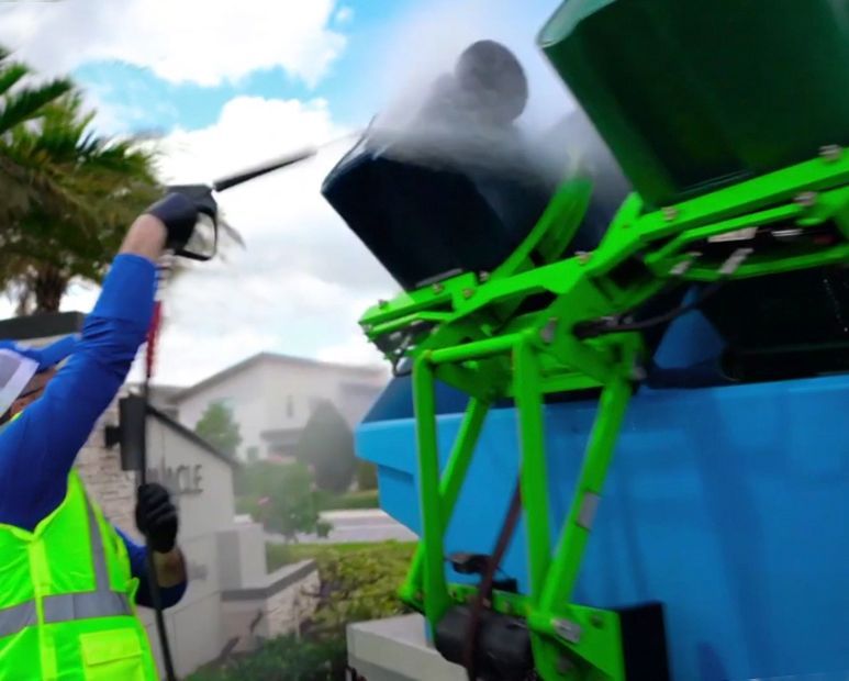 A person is holding a spray bottle over a trash can.