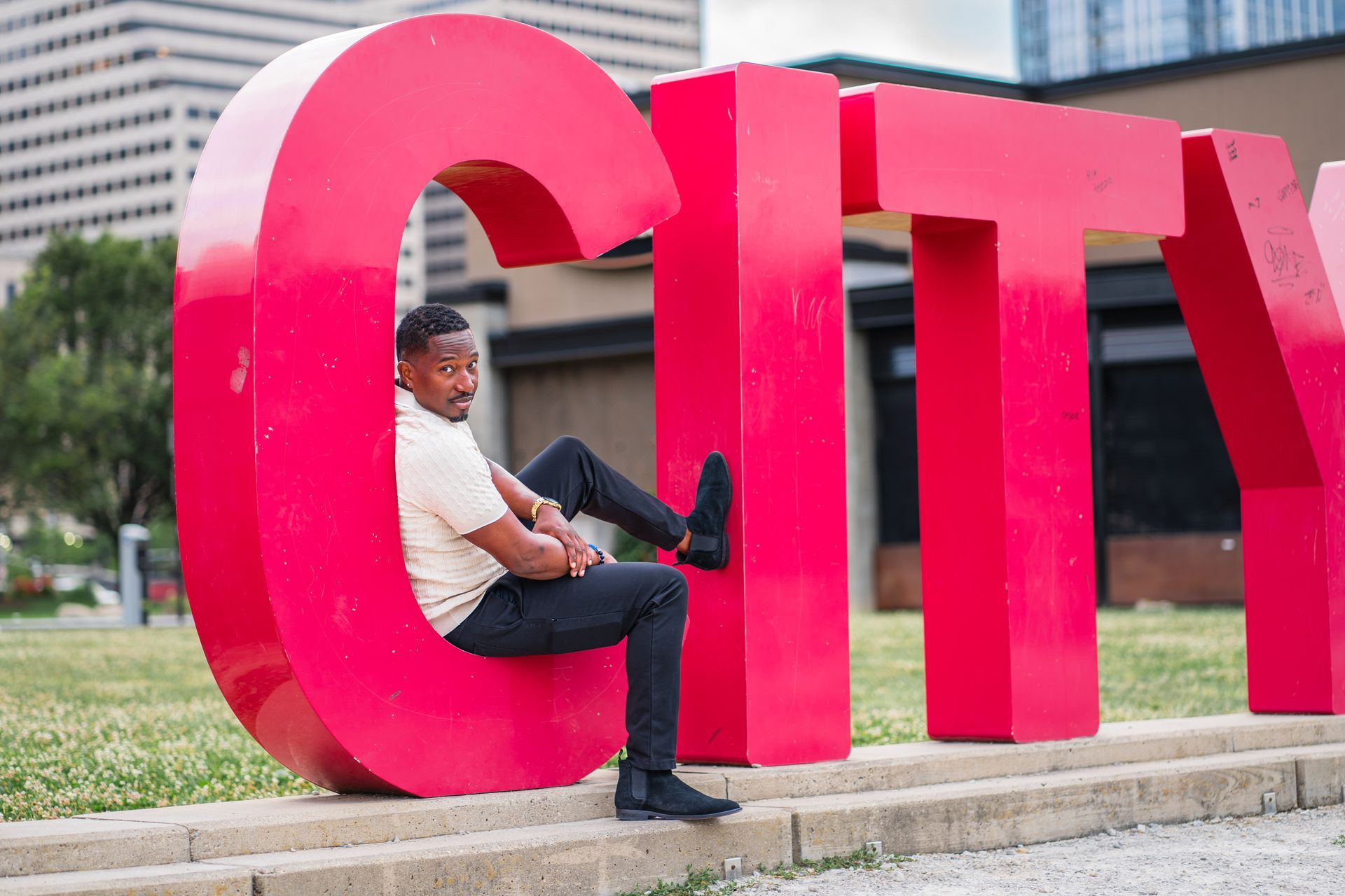 Corey Tucker is sitting on a large red city sign.